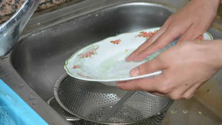 صورة تعبيرية لسيدة مغربية تغسل أطباق في منزل الأسرة